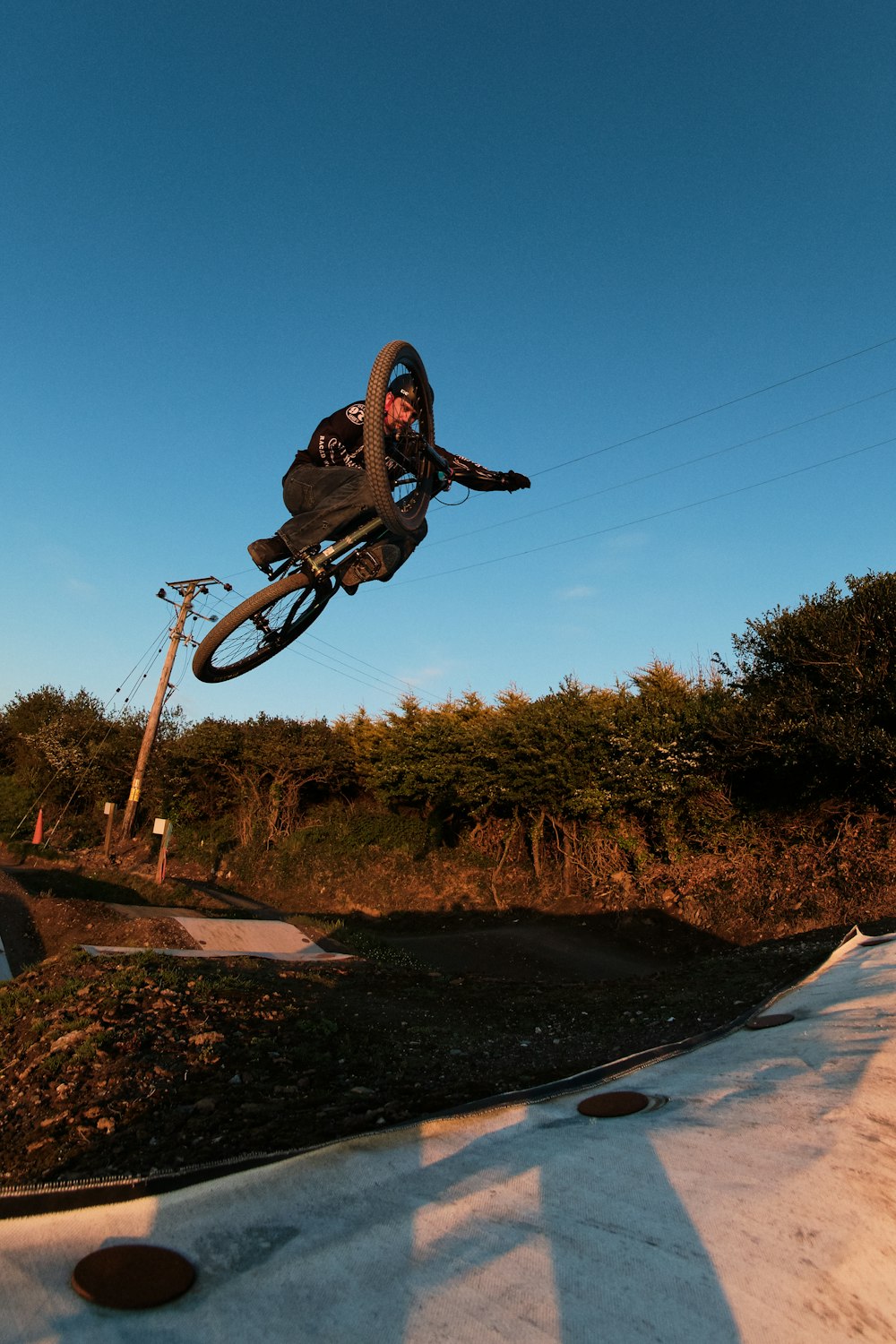 man riding on black bmx bike doing stunts on brown dirt road during daytime