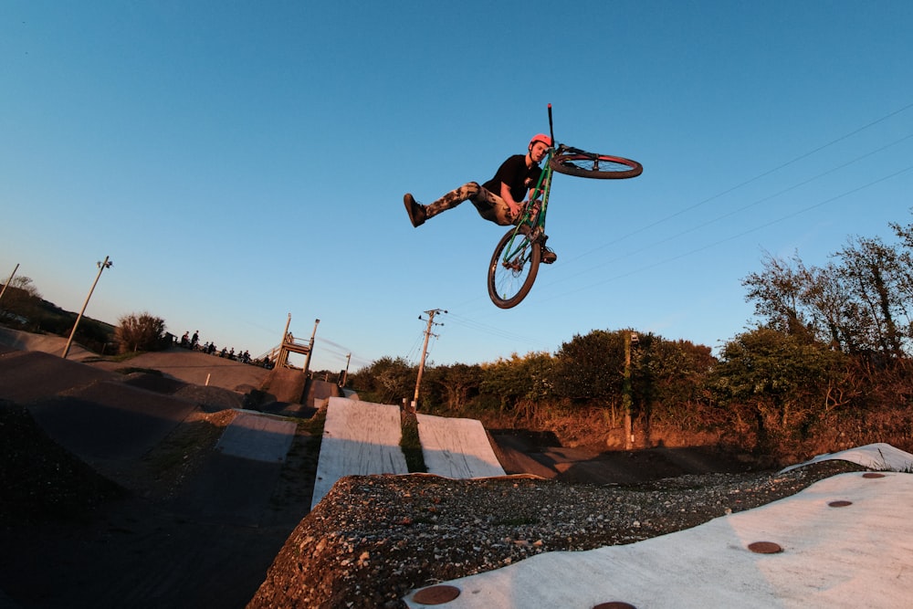 낮 동안 스턴트를 하는 검은색 BMX 자전거를 타고 녹색 재킷을 입은 남자