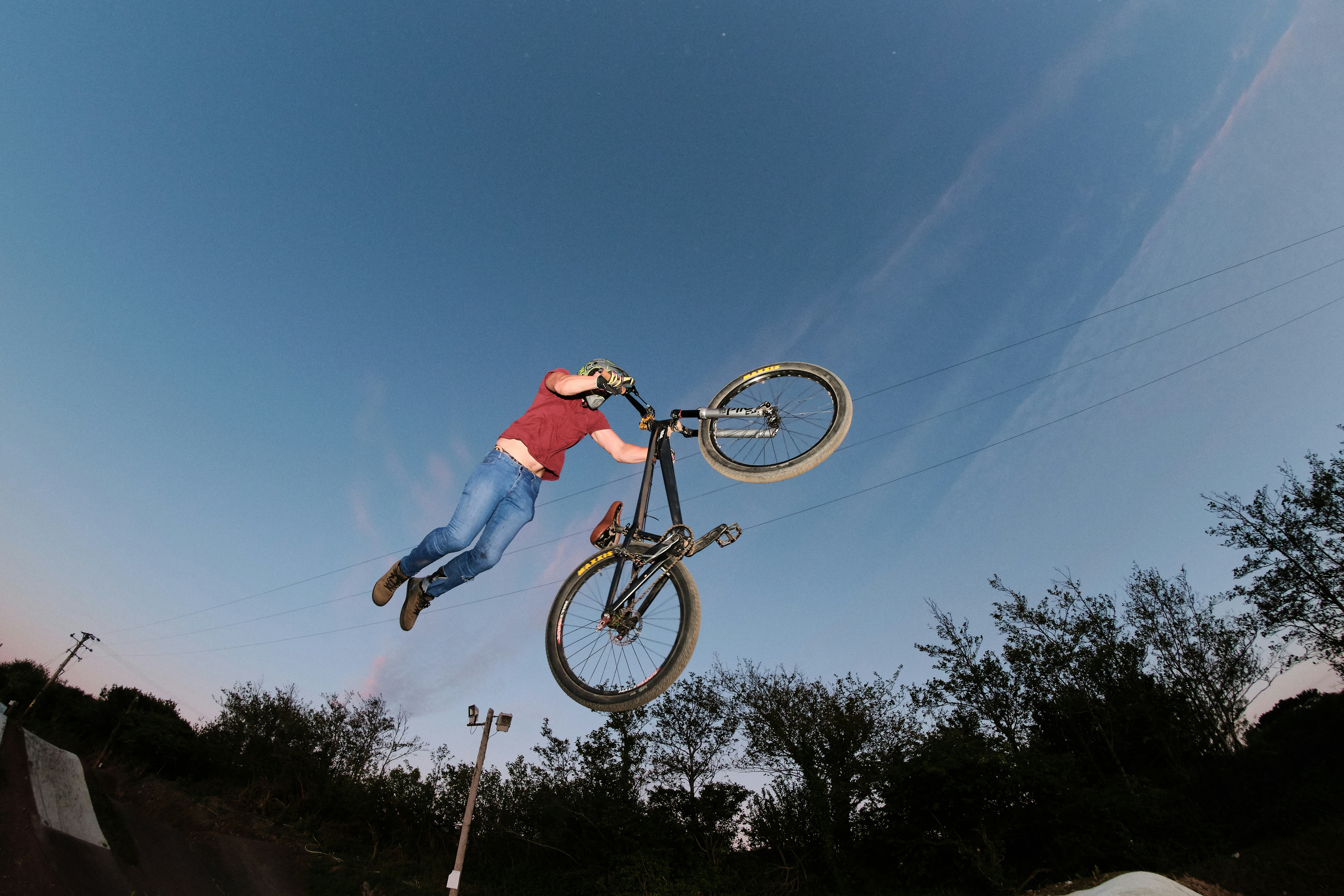 昼間に茶色の未舗装の道路でスタントを行う黒い Bmx バイクに乗っている男の写真 Unsplashで見つけるレッドルースの無料写真