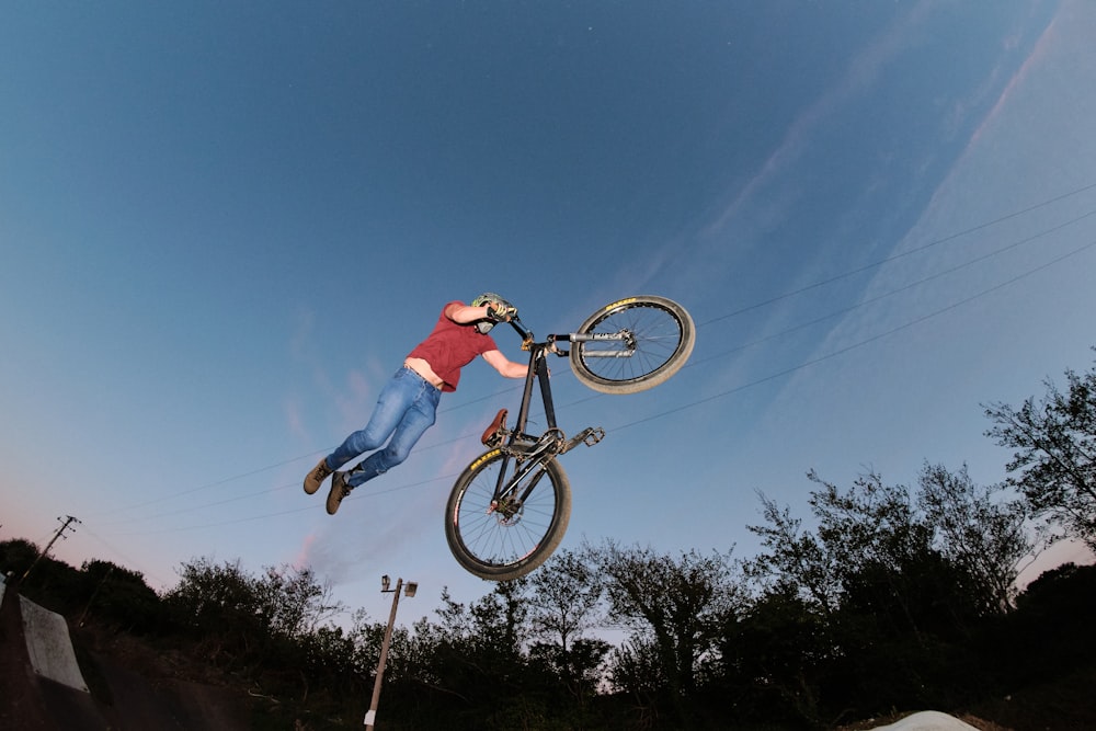 man in red shirt riding on black bmx bike