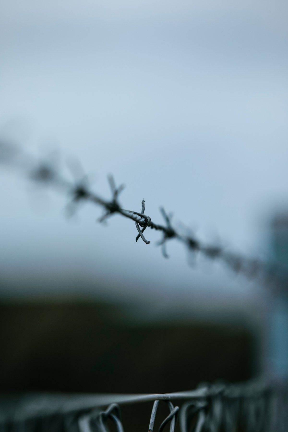 Blurry barbed wire fence against a blue background