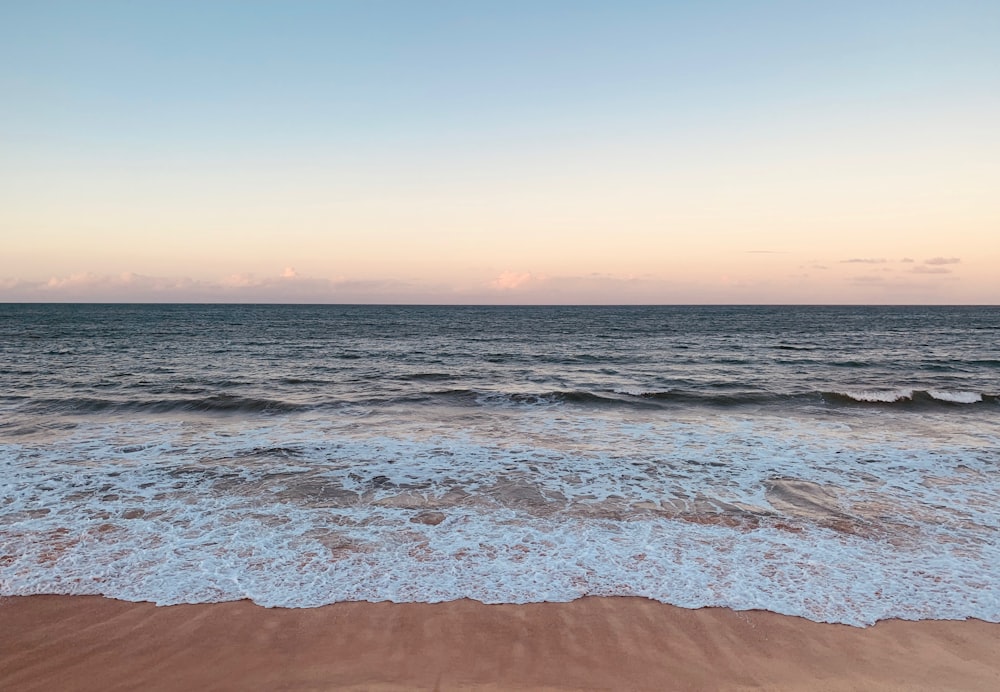 ocean waves crashing on shore during sunset