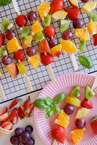 Elegant fruit brochettes arranged on a platter with a mix of melon, kiwi, and berries