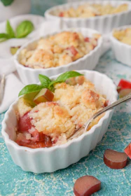 Warm fruit cobbler in a ceramic dish with a golden crust and bubbling filling.