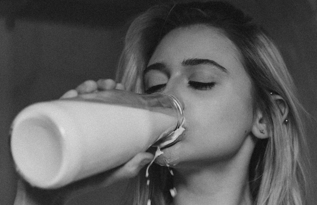 woman drinking milk from clear drinking glass