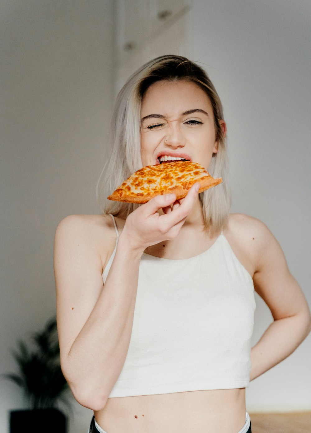 woman in white tank top holding pizza