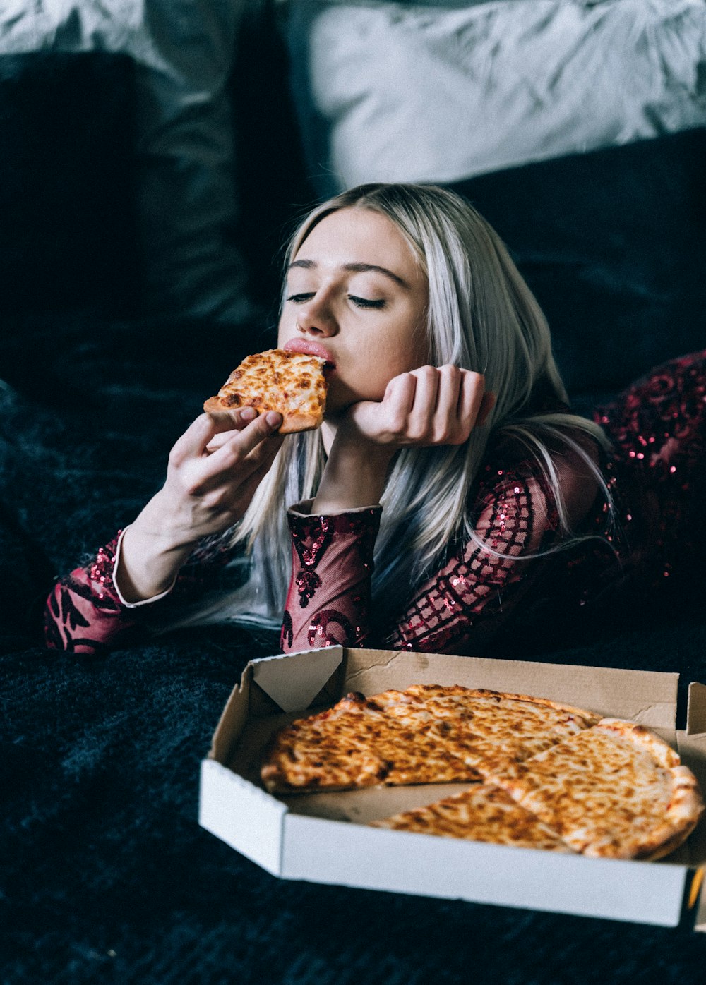 woman in red and black plaid long sleeve shirt eating pizza