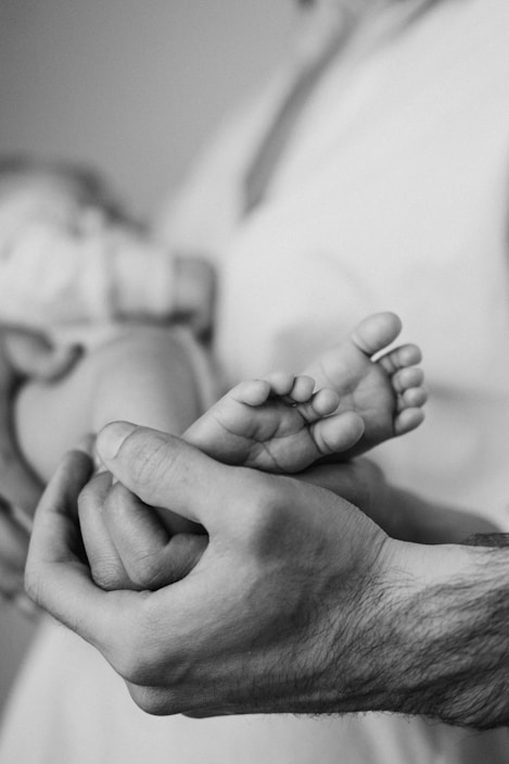 grayscale photo of person holding babys feet