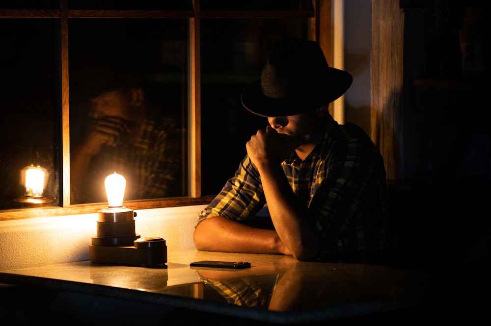 man in black and white plaid dress shirt wearing brown cowboy hat sitting beside table with with with with with