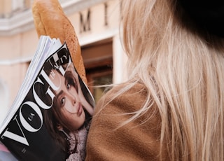 woman in brown coat holding magazine