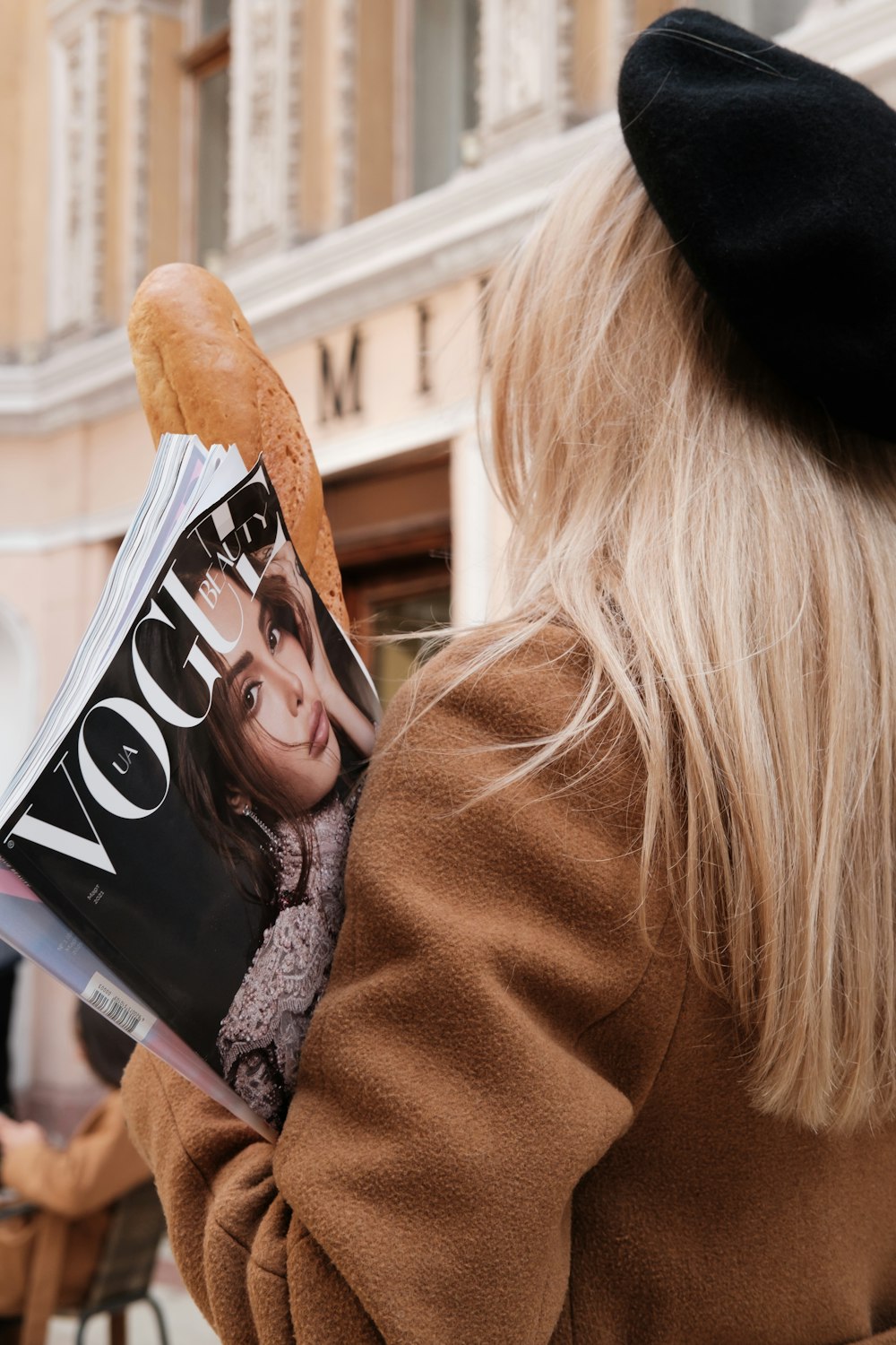 woman in brown coat holding magazine