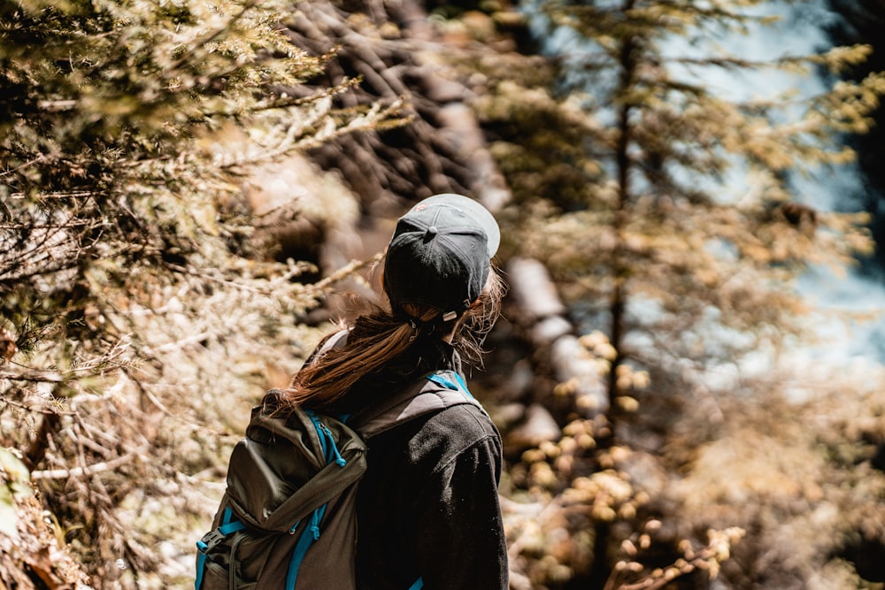 woman in black jacket and gray knit cap standing in front of brown trees during daytime