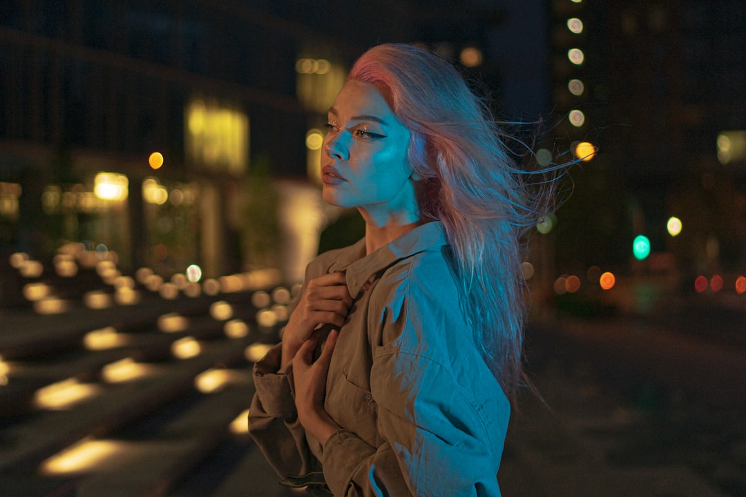 woman in brown coat standing on street during night time