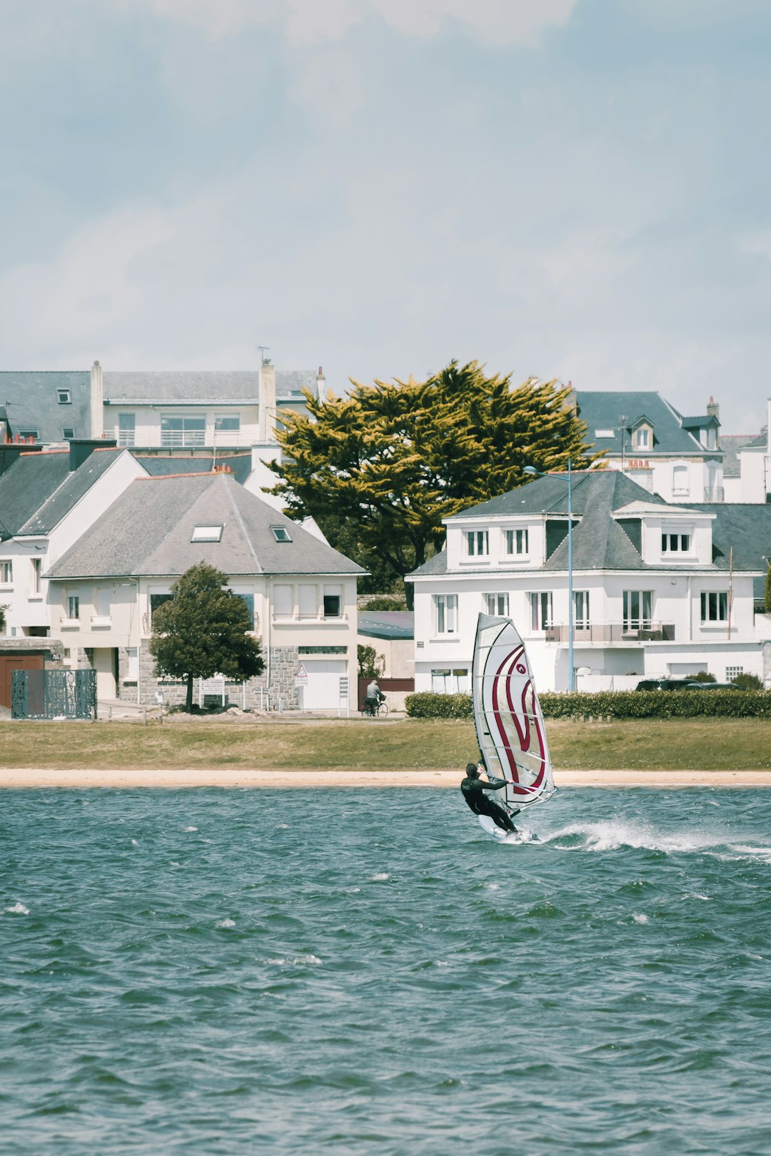 white and red sailboat on sea near white concrete building during daytime