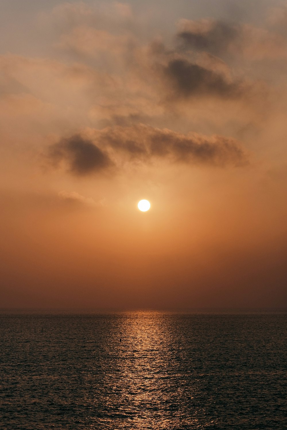 body of water under cloudy sky during sunset