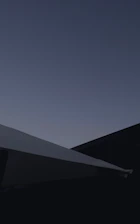 A minimalist architectural shot of a modern carbon processing facility blending into a natural forest backdrop under dusk light.