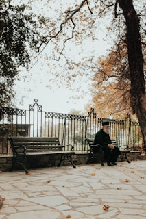 An elderly man sitting on a park bench, reflecting.