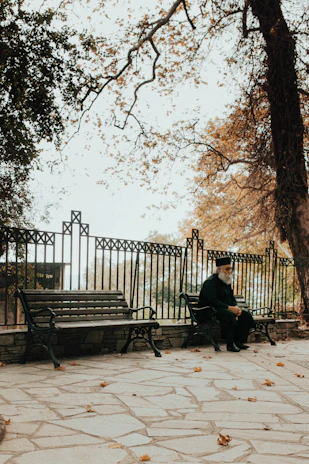 A serene park scene with a veteran wearing a service cap and reflecting quietly on a bench.