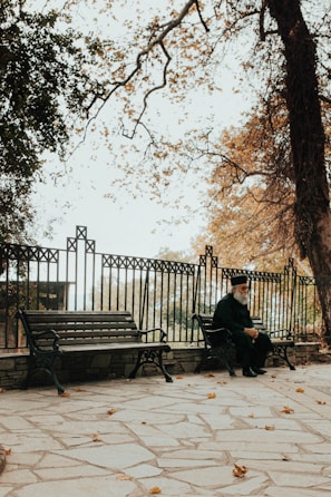 An elderly man sitting on a park bench, deep in thought.