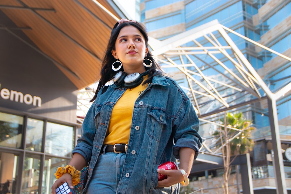 woman in blue denim button up jacket holding red apple fruit