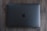 A closed, space gray laptop with a prominent black apple logo on the center of the top cover rests on a wooden surface.