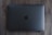 A closed, space gray laptop with a prominent black apple logo on the center of the top cover rests on a wooden surface.