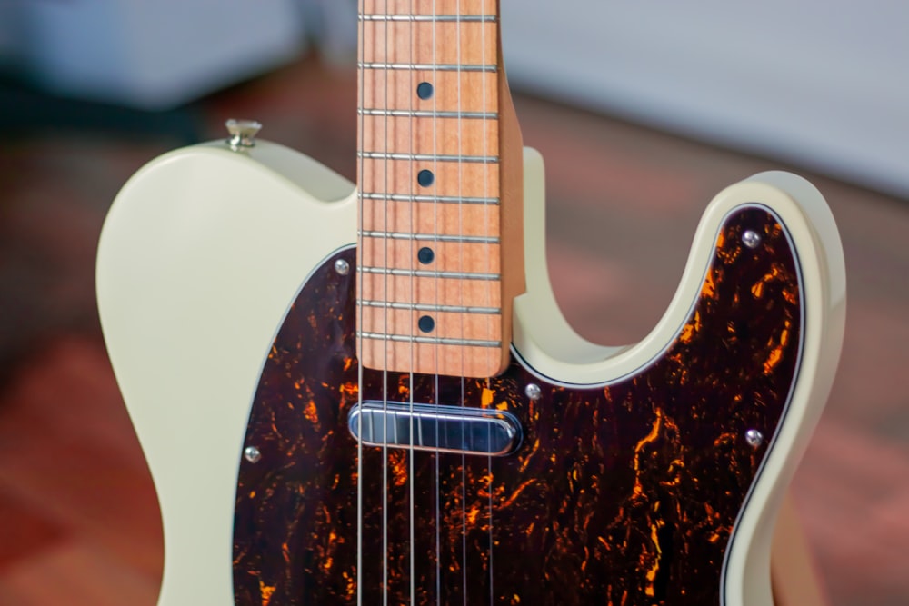 brown and white stratocaster electric guitar