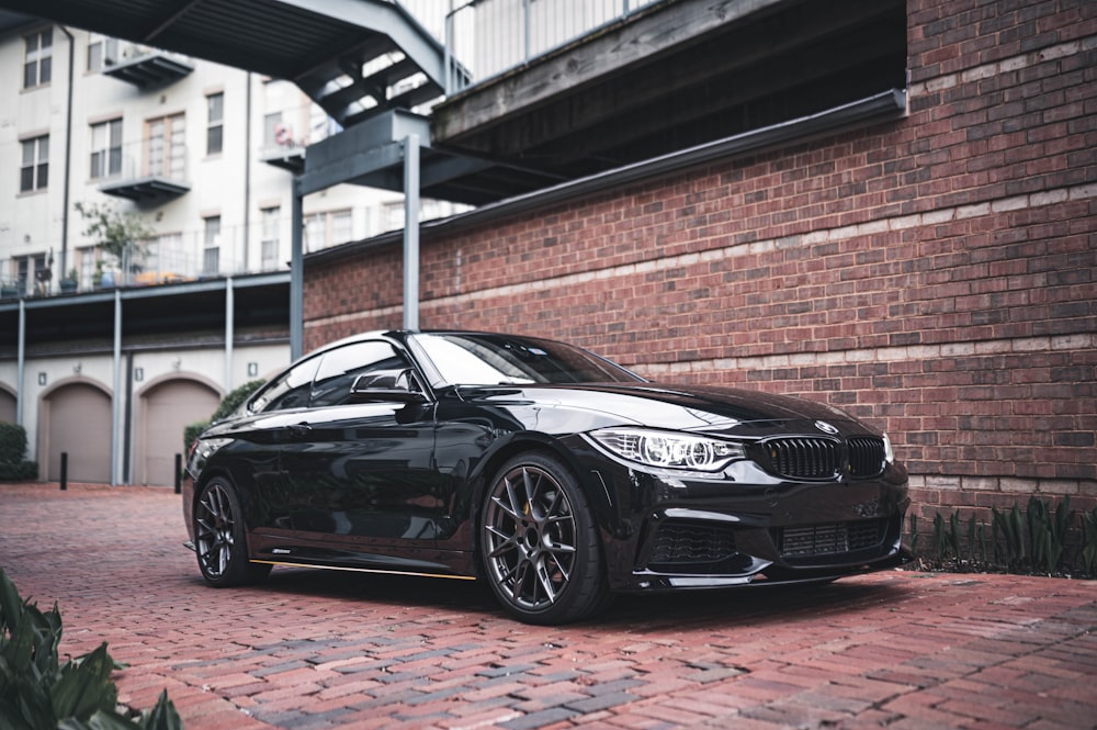 black bmw m 3 coupe parked beside brown brick wall