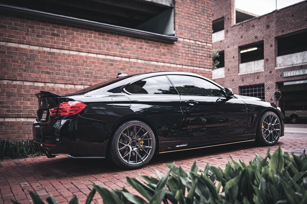 black sedan parked beside brown brick building