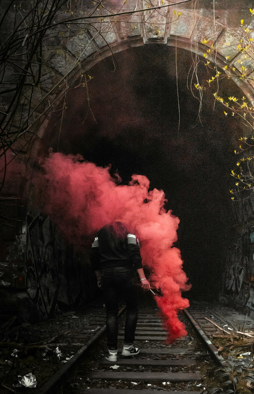 man in black jacket standing near red smoke