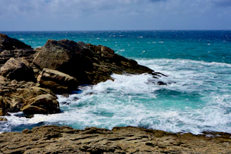 ocean waves crashing on rocky shore during daytime