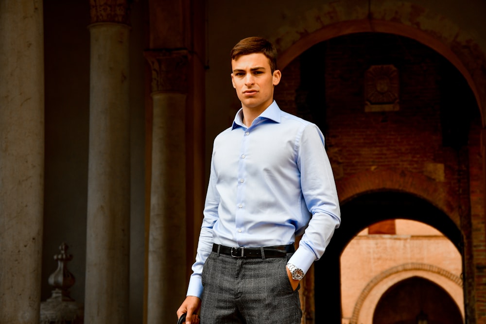 man in blue dress shirt and blue denim jeans standing on hallway