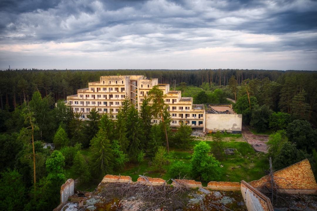 brown concrete building near green trees under white clouds during daytime