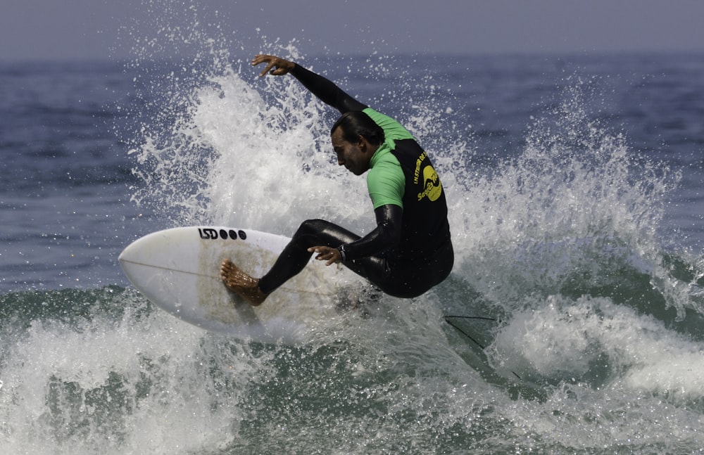 man in green and black wet suit surfing on sea waves during daytime