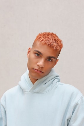boy in white hoodie standing near white wall