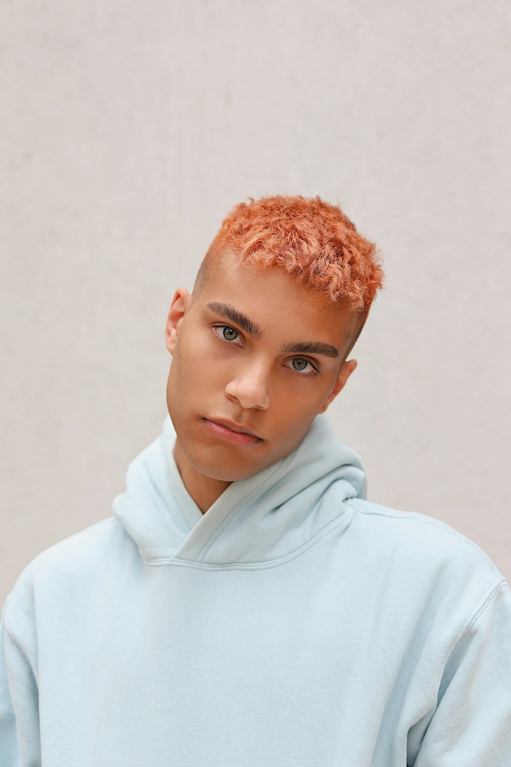 boy in white hoodie standing near white wall