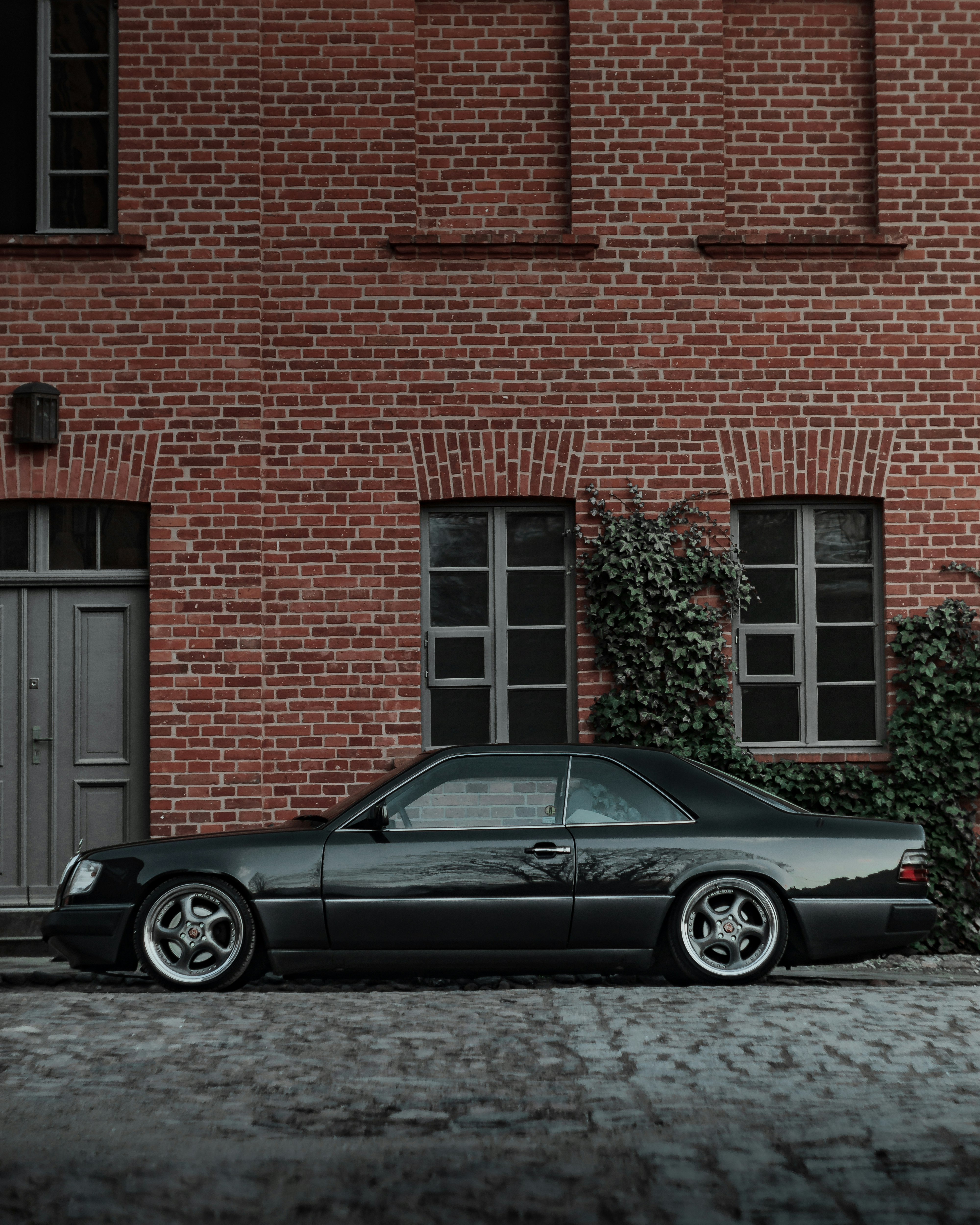 black coupe parked beside brown brick building
