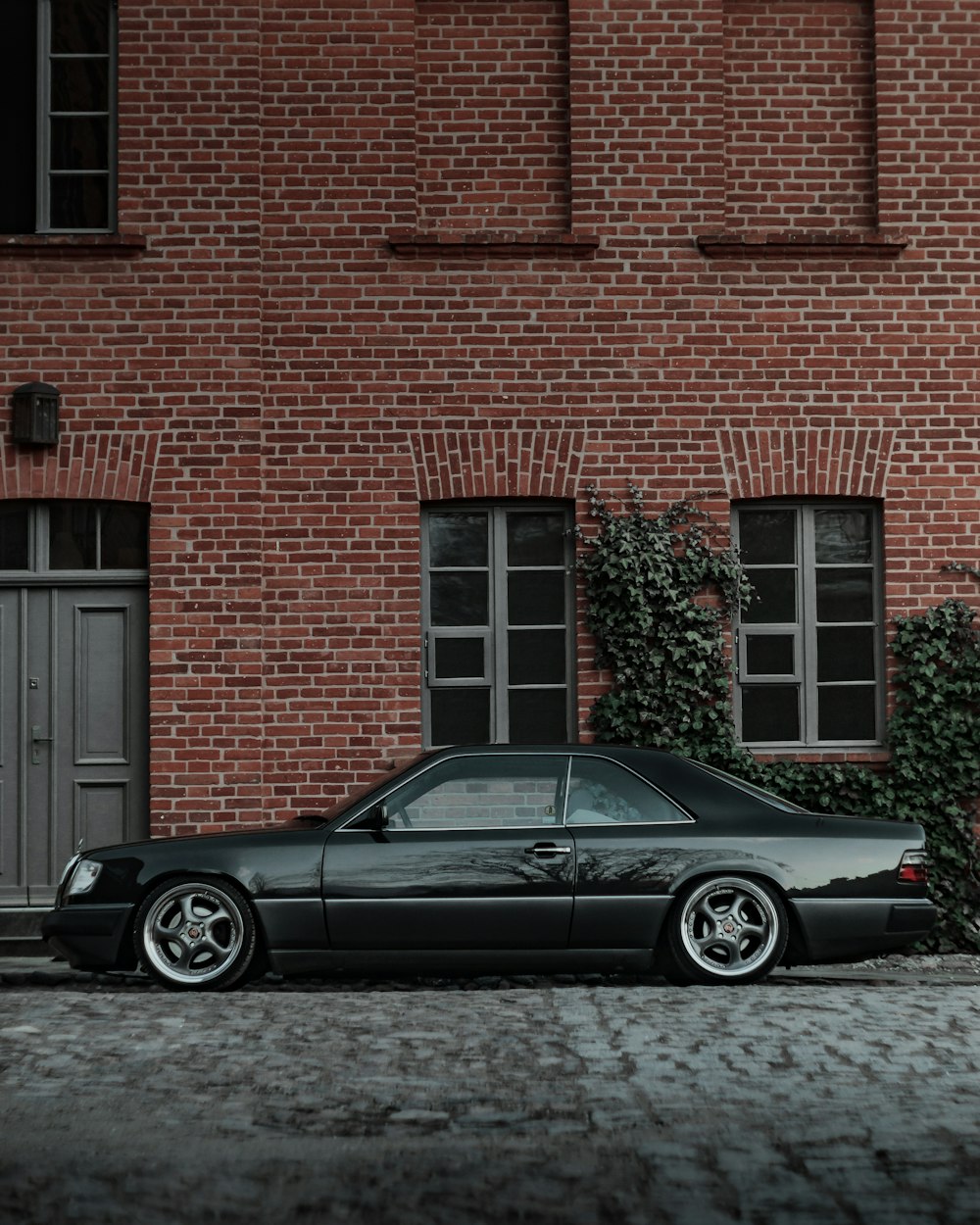 black coupe parked beside brown brick building