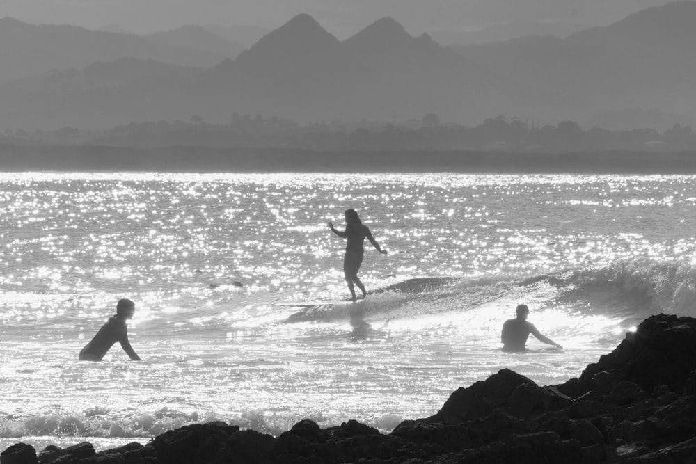 homem em traje de mergulho preto andando na costa da praia durante o dia