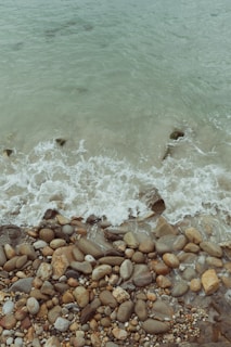 Soft waves lapping against smooth pebbles with a compass and star charm nearby