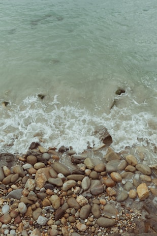 Soft waves lapping against smooth pebbles with a compass and star charm nearby