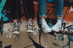 person in blue denim jeans wearing black and white converse all star high top sneakers