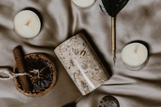 A serene flat lay of a journal, crystals, and a softly glowing candle on a white background.