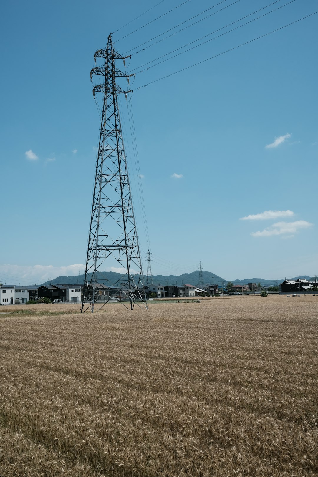 black electric tower on brown field under blue sky during daytime