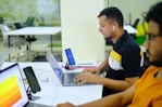 man in black and yellow polo shirt using macbook pro