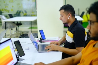 man in black and yellow polo shirt using macbook pro