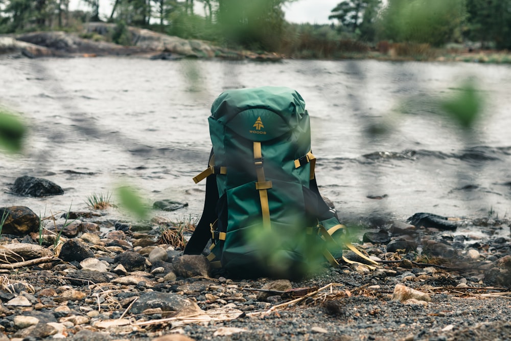 green and black hiking backpack on rocky shore during daytime
