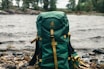 green and black backpack on brown wooden log
