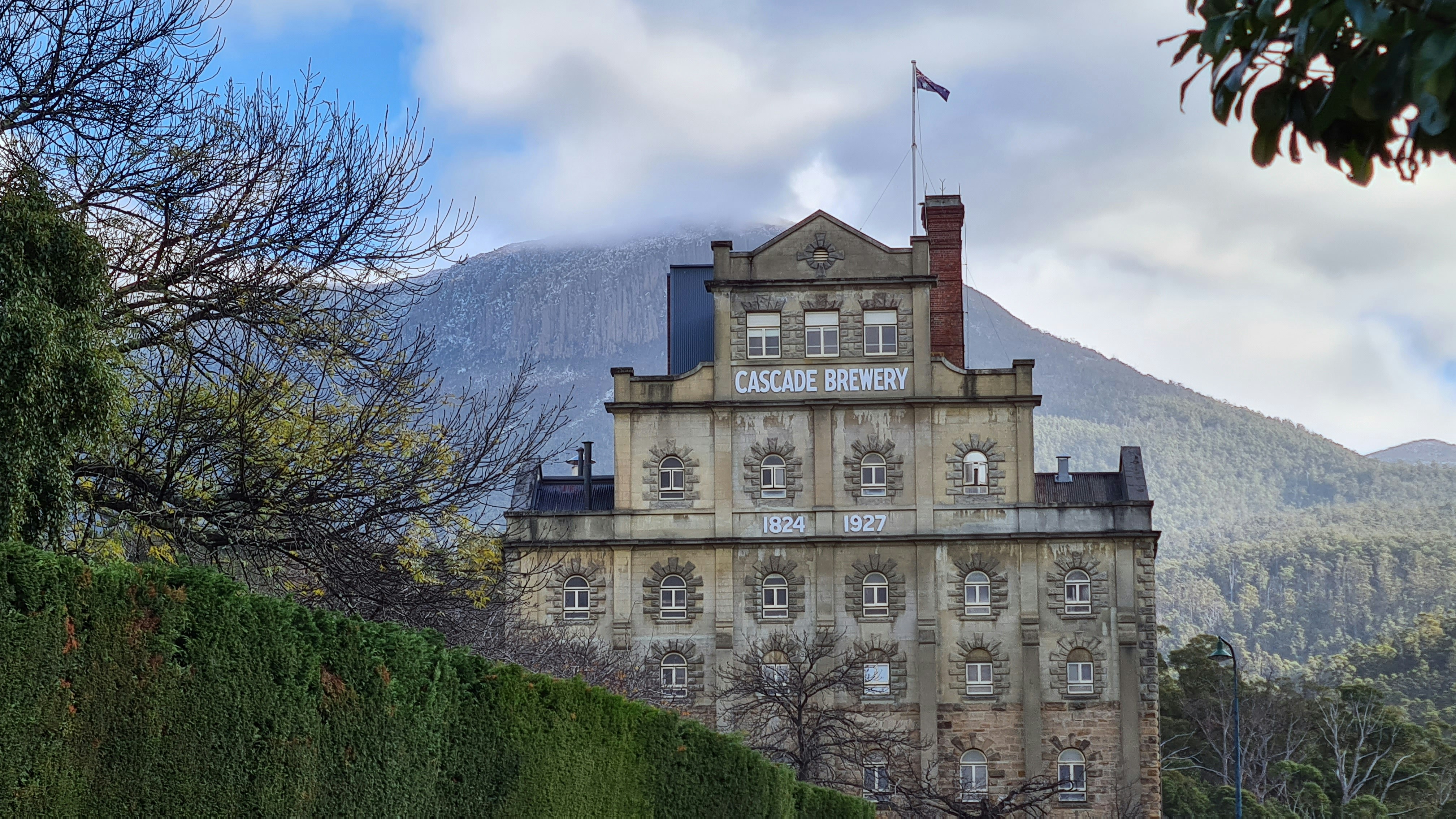 brown concrete building near green grass field and mountain during daytime