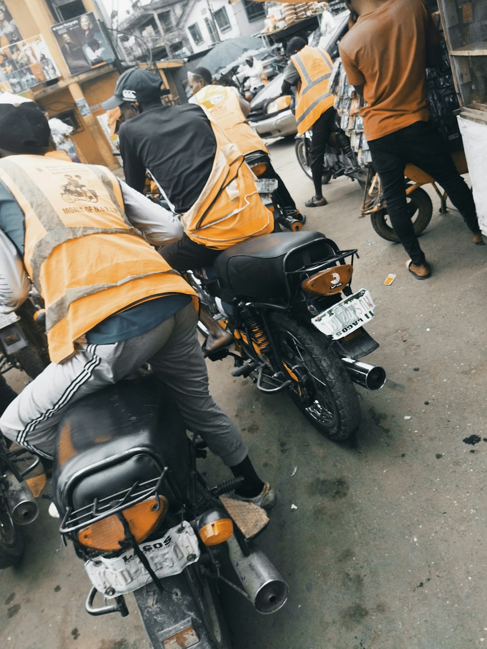man in orange jacket and black pants riding on black motorcycle